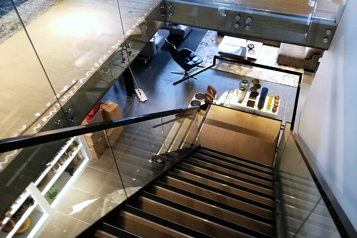 Black steel stair with a frameless glass balustrade, seen from the floor above