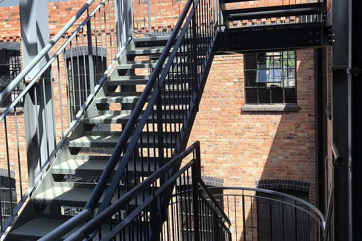 Grey steel escape stair flights and landings inside a brick stair tower